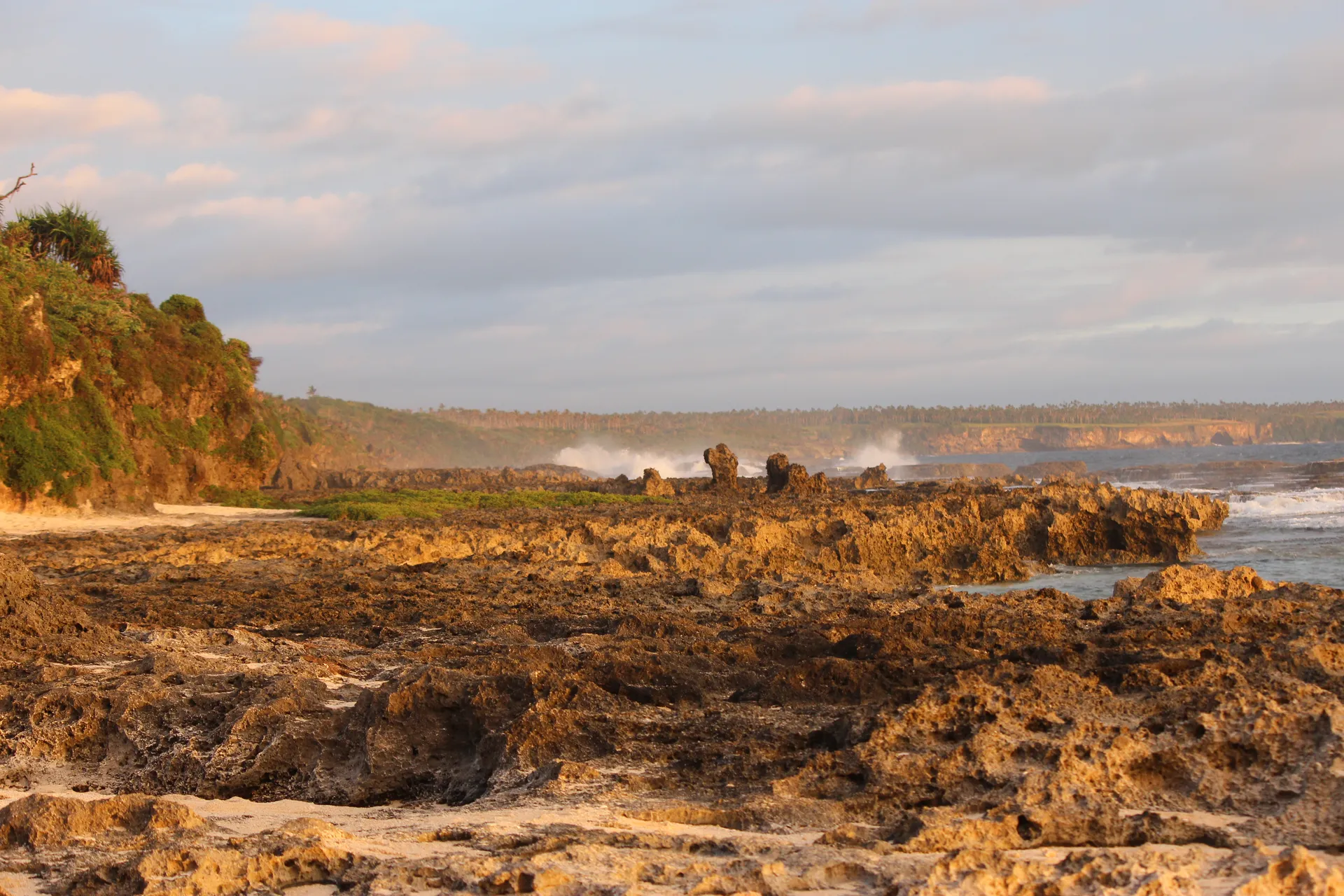 Low golden sun on the coral coast of southern Tongatapu, with spray rising off the reef.